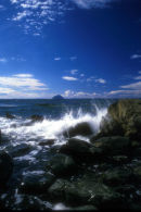 Waves splash over rock with Ailsa Craig in background