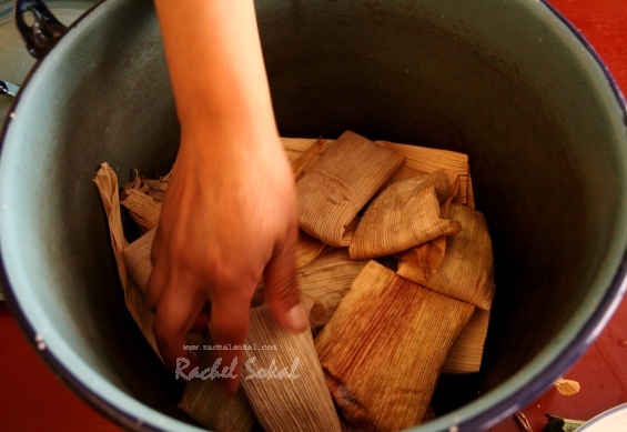 Juana puts the tamales into the pot - only one pair of hands, or they won't cook well!